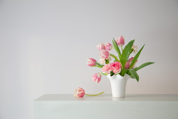 pink spring flowers in white ceramic vase in modern home interior