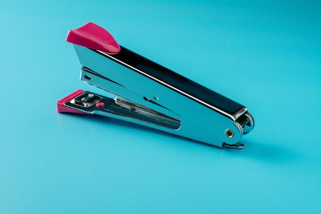 Pink stapler on a blue background