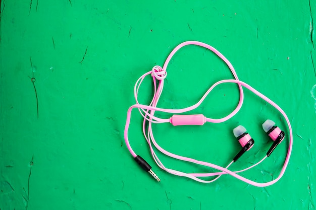 pink stereo earphones on wooden green