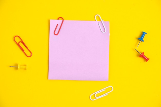 ペーパー クリップ黄色の背景を持つノートと文房具のボタンのピンクのステッカー