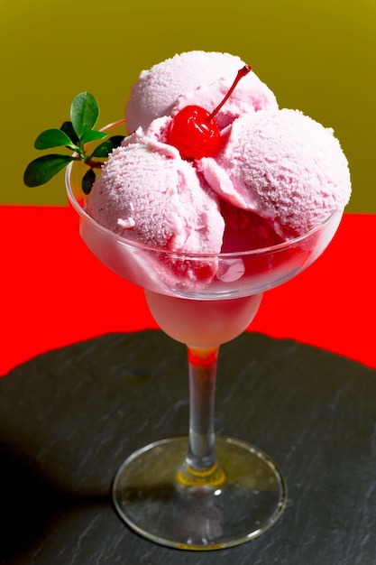 グラスに入ったピンク色のストロベリーアイスクリームとチェリーがトッピングされています。
