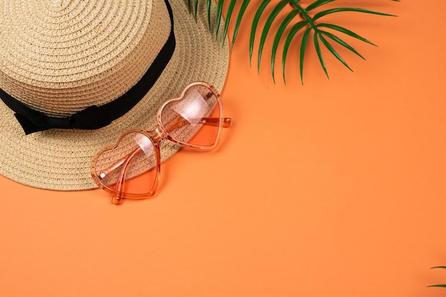 Pink sunglasses and a hat on orange background. Copy space.