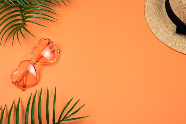 Pink sunglasses and a hat on orange background