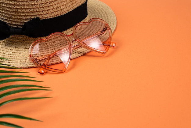 Pink sunglasses and a hat on orange