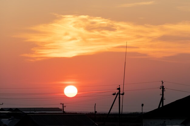 Pink sunset over the poles of power lines a large sun on the
horizon line between the wires