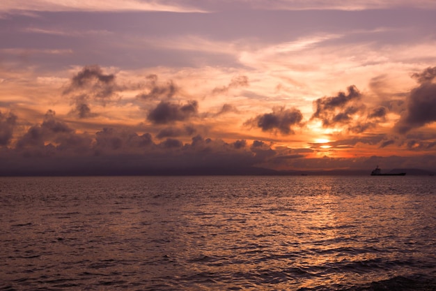 Pink sunset sky with many beautiful clouds over sea