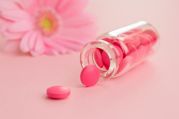 Розовые таблетки и стеклянная бутылка на свет.