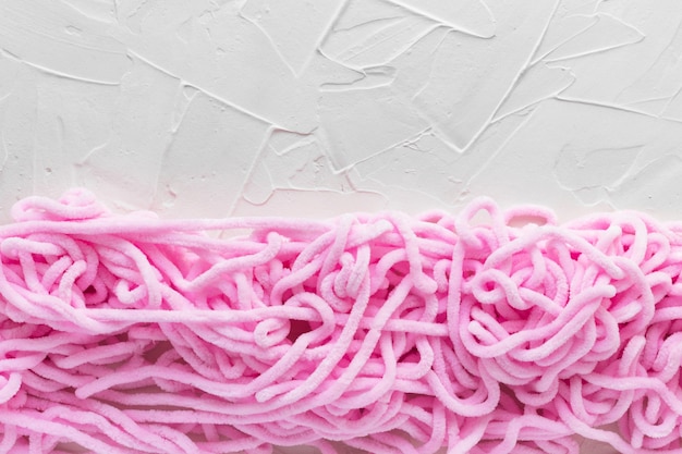 Pink tangled threads on white putty rextured background. Soft plush yarn for knitting. Needlework