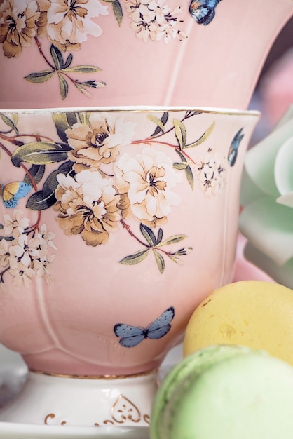 Pink tea cups with floral ornament and macaroon sweets