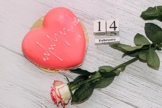 Pink tea rose with heart shaped pink mousse cake and February 14 calendar