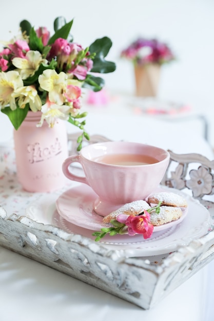 写真 テーブルの上の花とピンクのお茶セット
