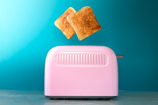 A pink toaster oven with leaping slices of fried bread