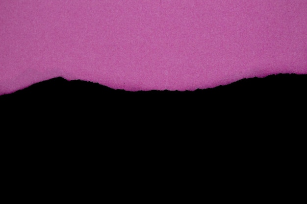 Pink torn paper on black background. Top view, copy space.