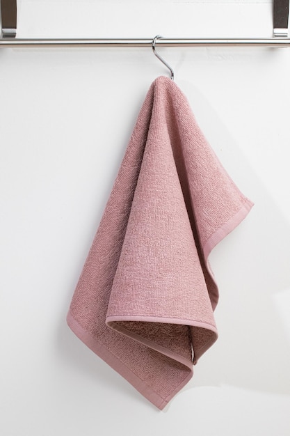 Photo a pink towel hanging on a white wall with a silver hook