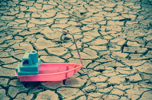 Pink toy boat is parked on the cracked ground