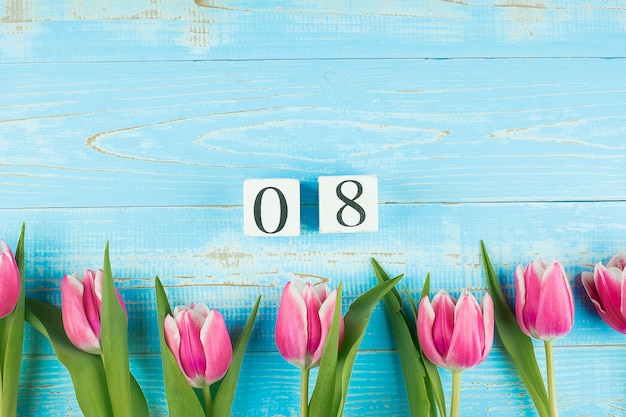 Розовый цветок тюльпана и 8-ое марта календарь на голубой деревянной предпосылке таблицы с космосом экземпляра для текста. Концепция любви, равноправия и Международного женского дня