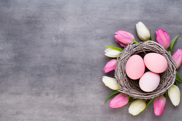 Pink tulip with pink eggs nest on a gray background. Easter greetings card.