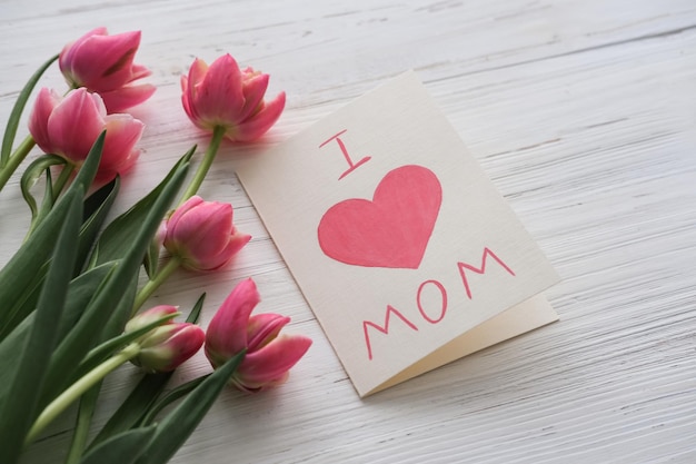 Pink tulips and a card with the text I love mom on a white background Mother's day concept