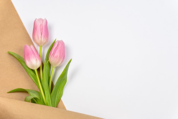 Pink tulips in craft paper on white background with copy space  Easter Valentines Day