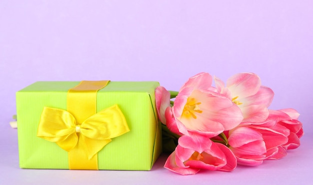 Pink tulips and gift box, on color background