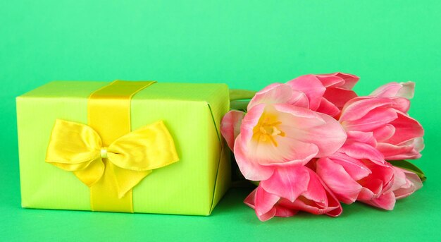 Pink tulips and gift box, on color background