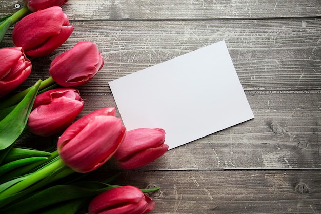 Pink Tulips and gift card on a wooden background Space for the text Top view Pink