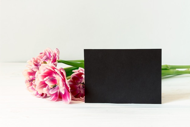 Розовые тюльпаны и горизонтальная черная бумага пустые открытки на день Святого Валентина.