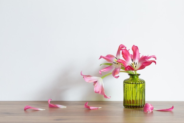 Фото Розовые тюльпаны в стеклянной зеленой вазе на белом фоне