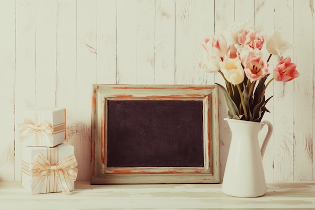 Pink tulips in jug and green wooden chalkboard. Teacher's day concept