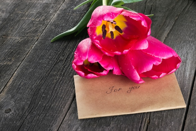 Pink tulips and message against a dark background