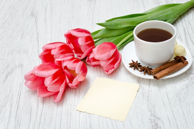 Pink tulips, mug of coffee and cinamon.