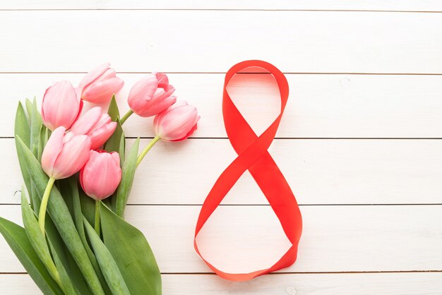 Photo pink tulips and red number eight for international womens day over white wooden table background with copy space