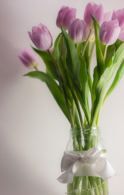 Photo pink tulips in vase against wall at home