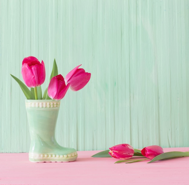 Pink tulips in vase on green wooden