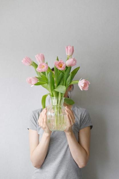 Pink tulips with green leaves in a glass vase