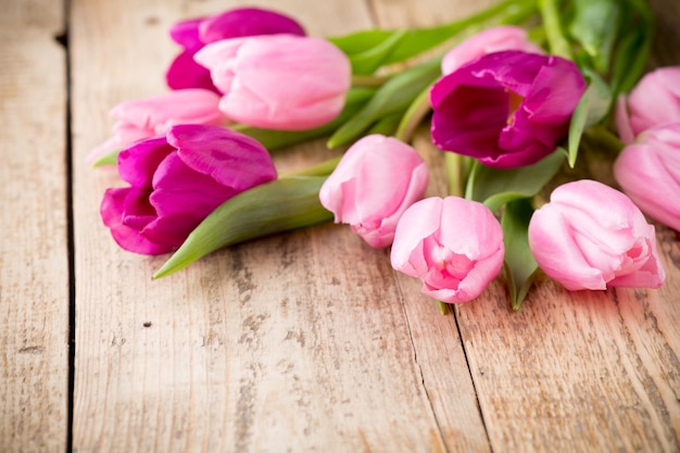 Pink tulips on wooden surface