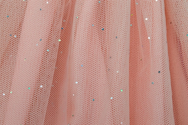 Pink tulle background with folds and sparkling sequins.