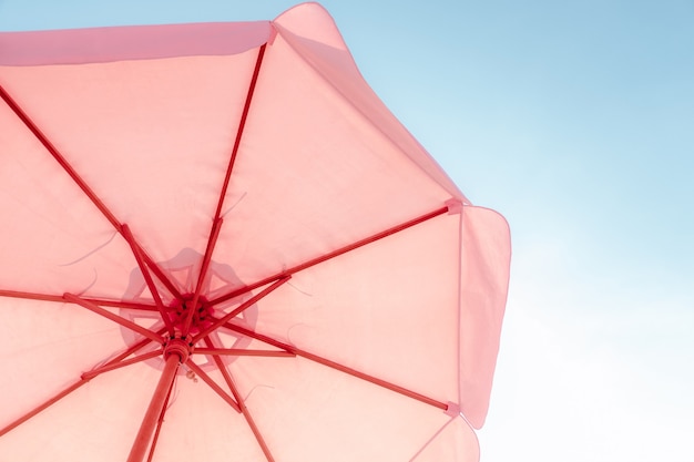 Pink umbrella against the sky on a chill vacation. Summer Holiday and Travel Concept