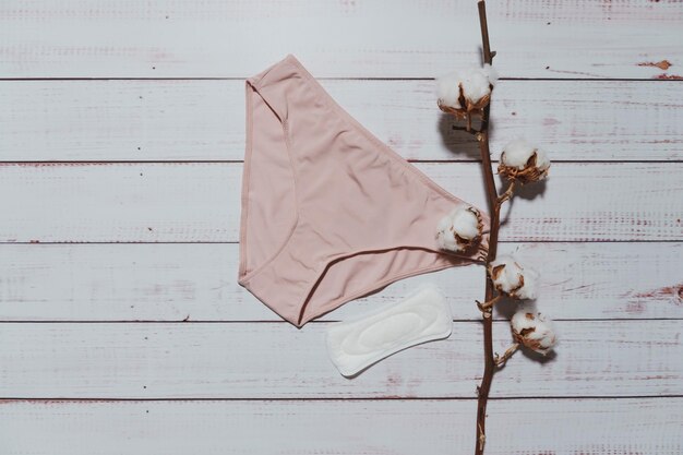 Pink underpants with cotton brunch on wooden background closeup