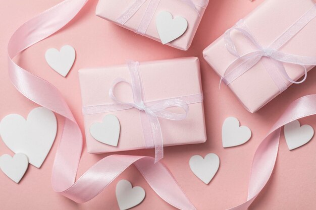 Pink valentine gift with white hearts on a pastel pink background