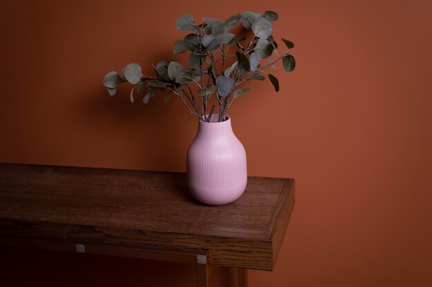 Foto un vaso rosa con dentro una pianta verde si trova su un tavolo