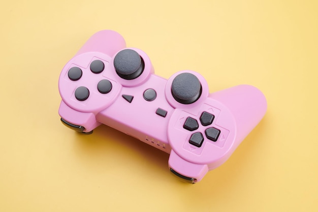 Pink video game controller joystick for game console isolated on yellow background Gamer control device closeup