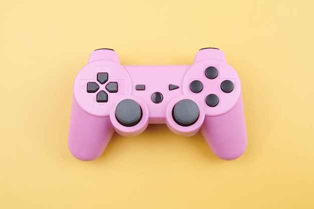 Pink video game controller joystick for game console isolated\
on yellow background gamer control device closeup