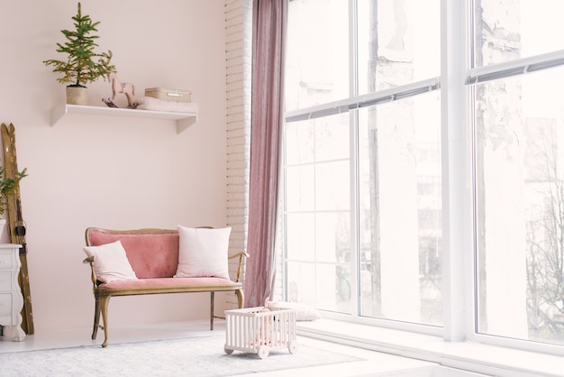 A pink vintage sofa with pillows stands near the window in the living room or children's room