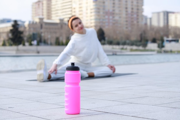 Photo pink water bottle on the ground young girl doing her exercises high quality photo