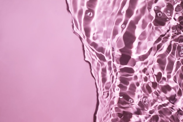 Pink water surface texture with splashes and bubbles Abstract background for beauty products