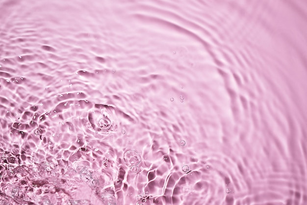 Pink water surface texture with splashes and bubbles Abstract background for beauty products