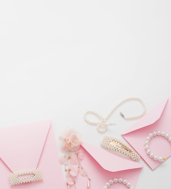 Pink wedding invitations are decorated with jewelry for the bride, with copy space.