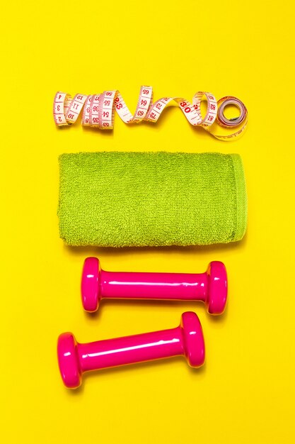 Pink weights with a green towel and a tape measure