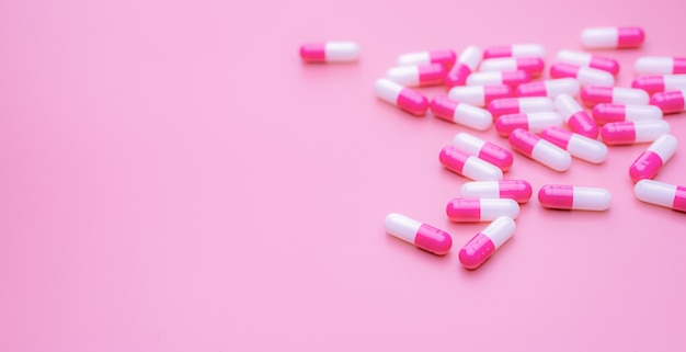 Pink-white antibiotic capsules pill spread on pink surface